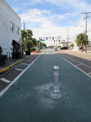 Photo of a green, paved bike trail along a street.