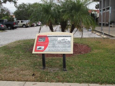 Photo of a red and tan graphic panel sitting in front of small palm trees.