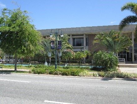Photo of a streetlight pole with banners hung on the sides, and a building in the background.