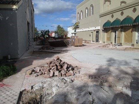 Photo of broken pavement in a courtyard between two buildings.