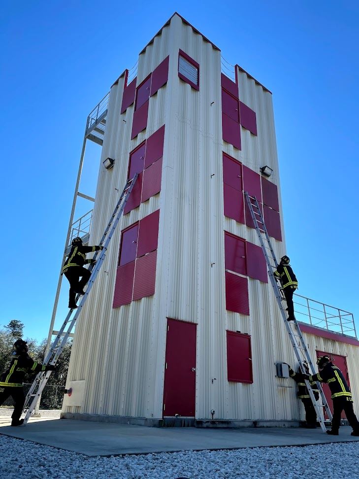 Firefighters climbing ladder against training tower